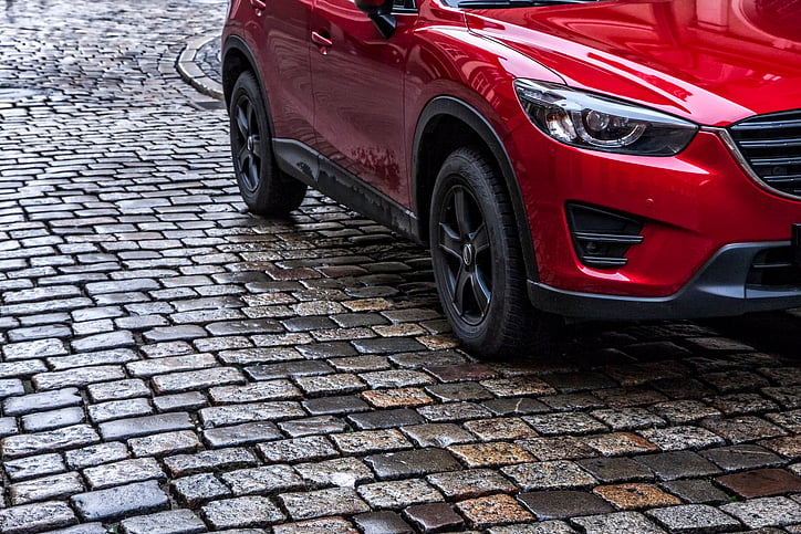 Red SUV’s front wheel and bumper on a wet cobblestone street.jpg